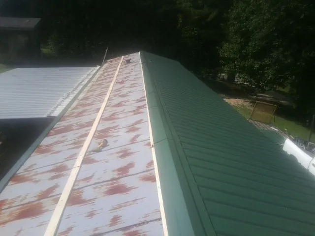 Old rusted panels beside newly installed green metal roofing — Wind Damage Roof Repair by Roofing Brothers in Marathon