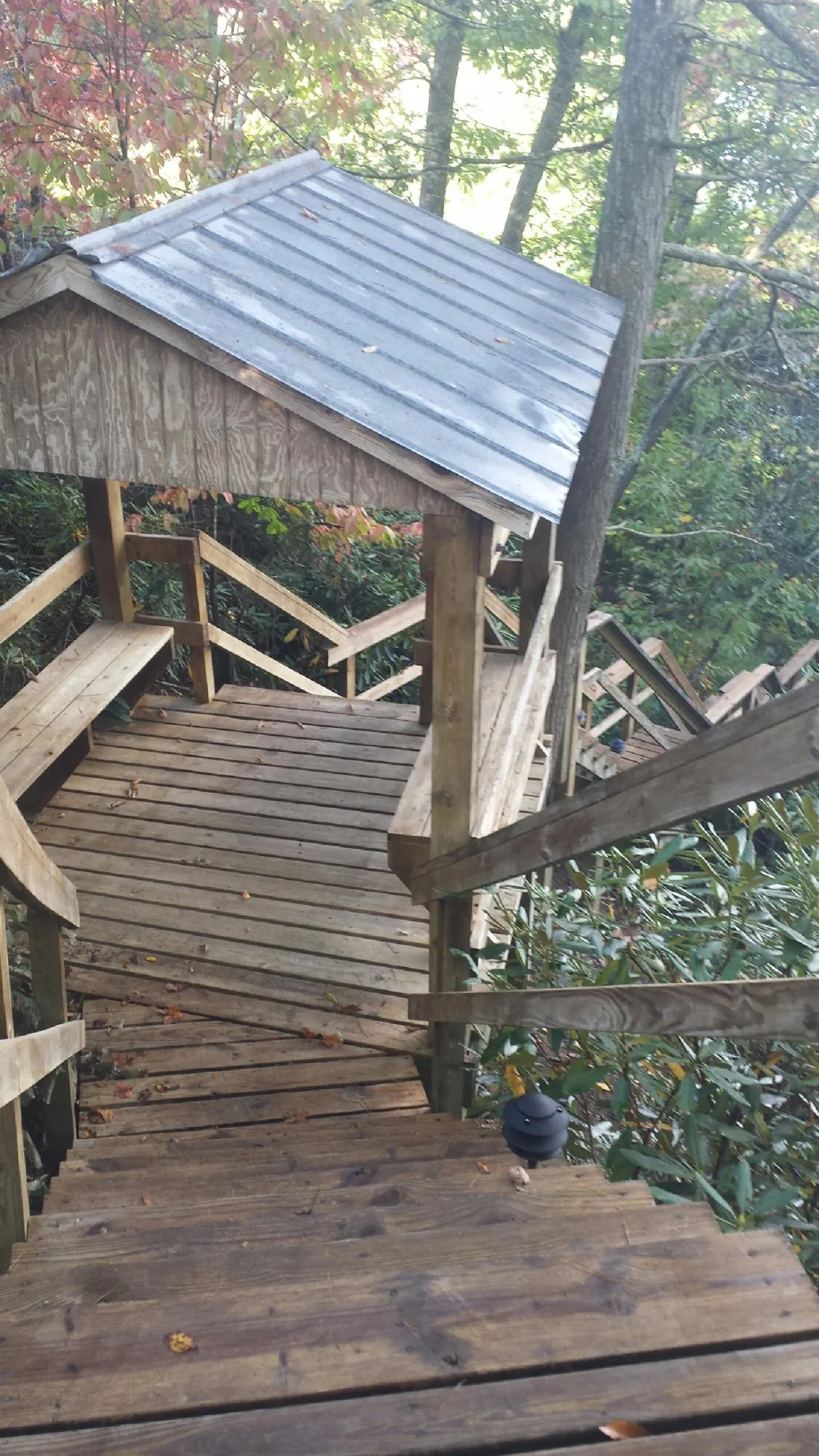 Metal roofed shelter over wooden steps on a wooded walkway — Skylight Repair & Installation work by our crew in Marathon